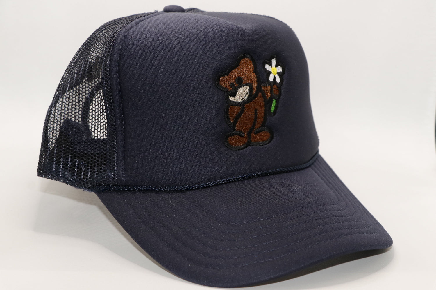 Solid Dark Blue Trucker Hat with a Brown Bear holding a Magnolia Daisy Flower